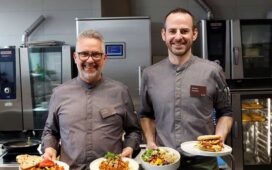 Thomas Mindrup (l. im Bild) und Markus Sandfort (r. im Bild) vom EAT-Team präsentieren die KI-gerierten Gerichte Ägyptischer Koshari, das Piri-Piri Hühnchen, die Quinoa-Bowl und den Hawaii-Burger. Sie stehen im April auf dem Speiseplan im EAT.
